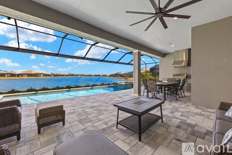 A patio with a table and chairs overlooking a pool.