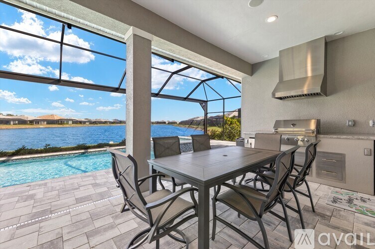 A table and chairs are set up on a patio with a view of a pool and a beach.