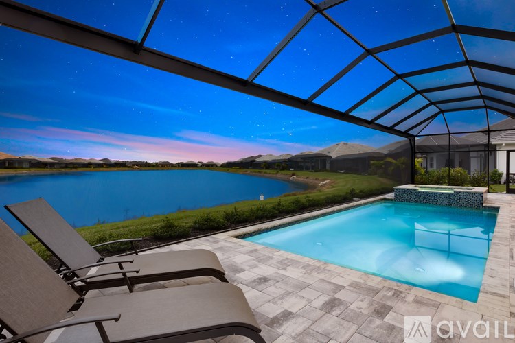 A swimming pool under a glass roof with lounge chairs on the side.