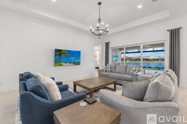 A living room with a blue armchair, grey sofa, and a painting of a beach scene on the wall.