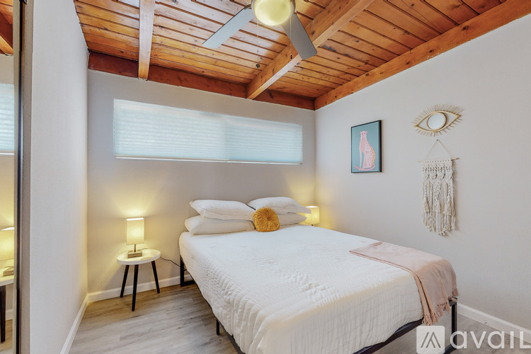 A bedroom with a bed, a lamp, and a dream catcher hanging on the wall.