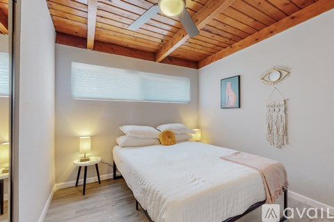 A bedroom with a bed, a lamp, and a dream catcher hanging on the wall.