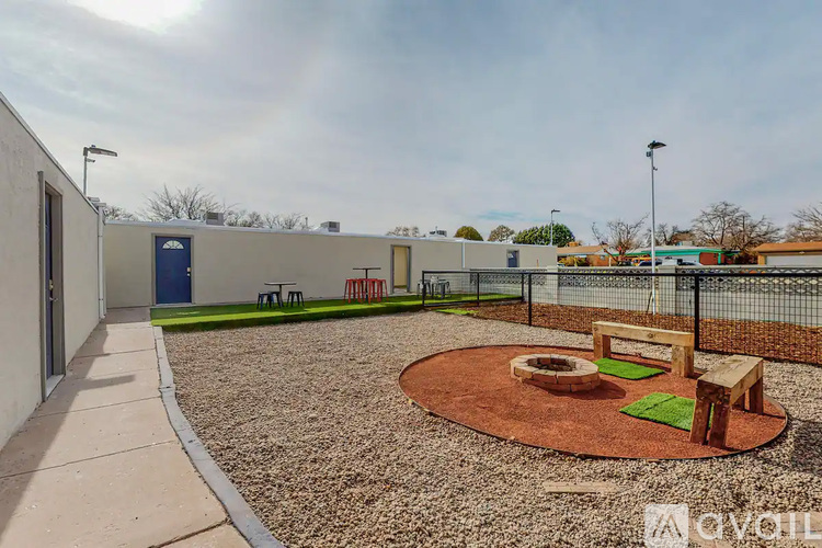 A playground area with a round sandbox and wooden benches.