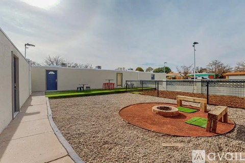 A playground area with a round sandbox and wooden benches.