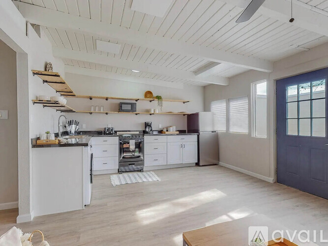A kitchen with white cabinets and a wooden floor.