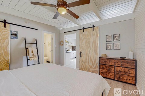 A bedroom with a bed, dresser, and ceiling fan.
