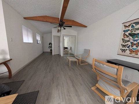 A living room with a ceiling fan and a painting on the wall.