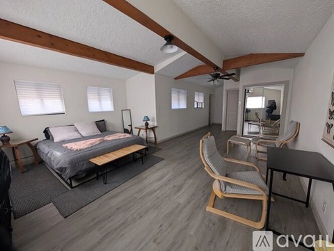 A bedroom with a bed, chair, and a ceiling fan.