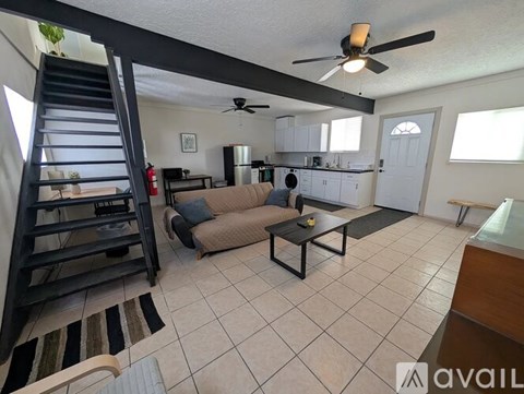 A living room with a couch, a coffee table, and a staircase.