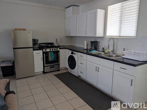 A kitchen with white cabinets and a black countertop.