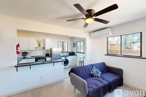 A living room with a blue couch and a kitchen area in the background.