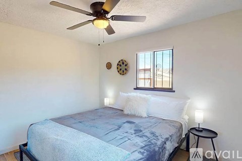 A bedroom with a bed, a ceiling fan, and a window.