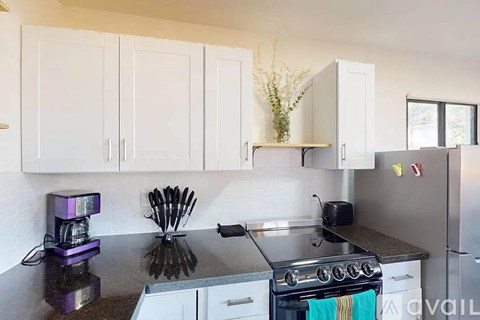 A kitchen with white cabinets and a black countertop.