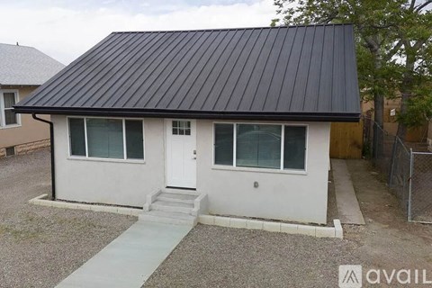 A house with a black roof and white walls is available for rent.