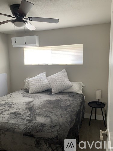 A bedroom with a bed, a fan, and a window with blinds.