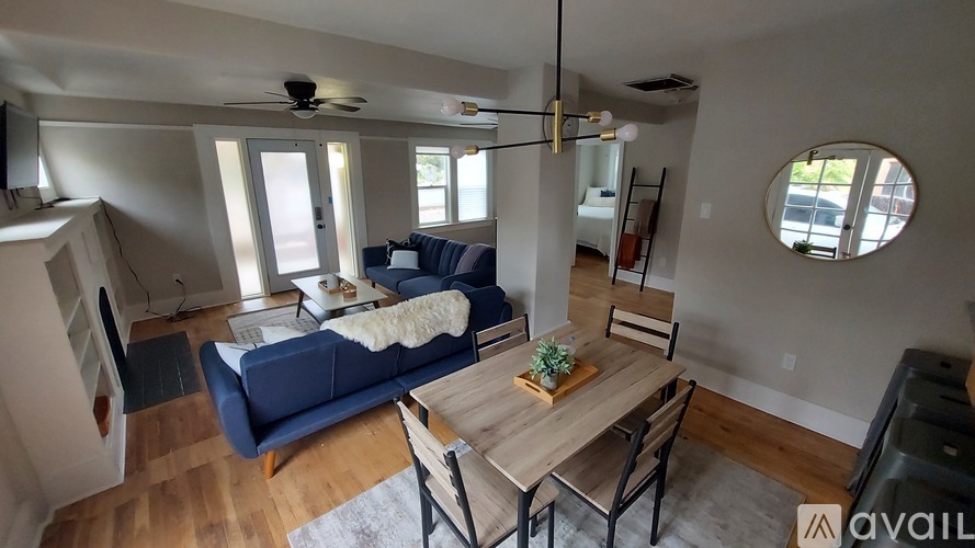 A living room with a blue couch, a wooden table, and a ceiling fan.