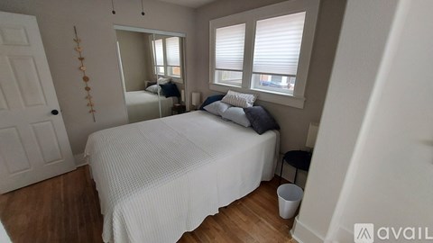 A bedroom with a white bed and a white door.