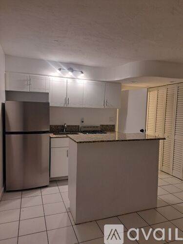 A kitchen with a refrigerator, cabinets, and a countertop.
