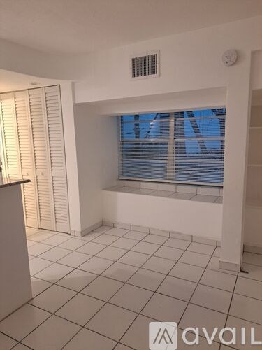 A room with a window covered by blinds and a tiled floor.