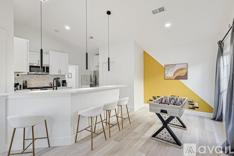 A modern kitchen with white cabinets and a bar area with stools.
