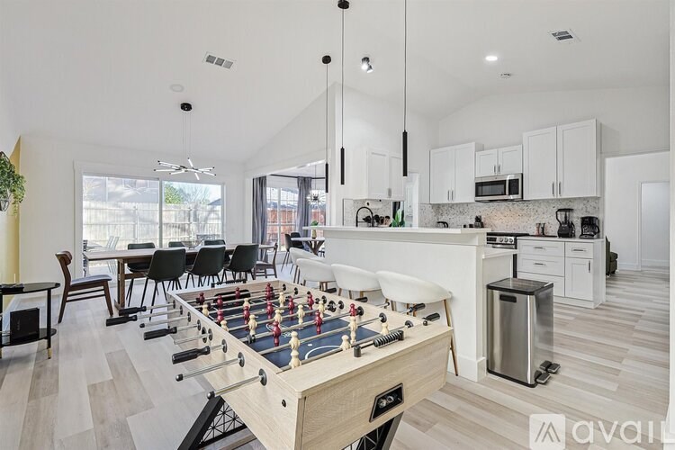 A foosball table is in the middle of a kitchen and dining area.