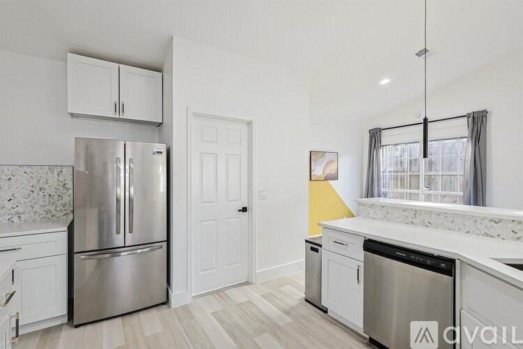 A kitchen with a stainless steel refrigerator, white cabinets, and a marble countertop.