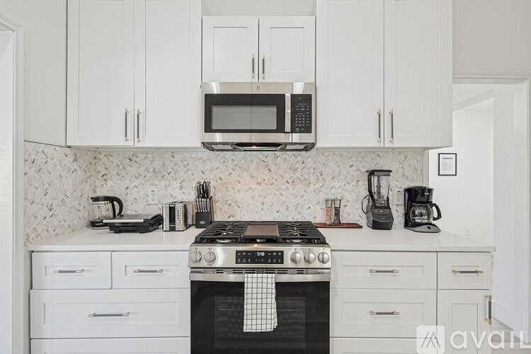 A kitchen with white cabinets and a black stove top.