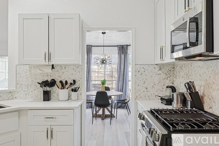 A kitchen with white cabinets and a marble countertop.