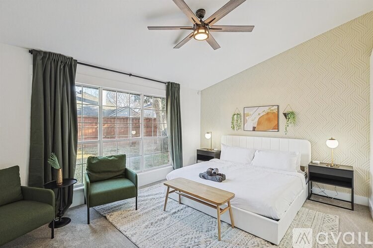 A bedroom with a bed, chair, and a table.