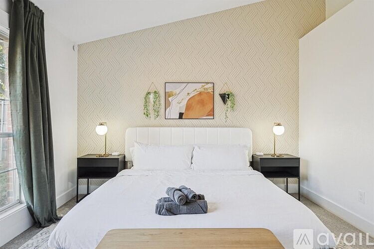 A bedroom with a large bed, two nightstands, and a painting on the wall.