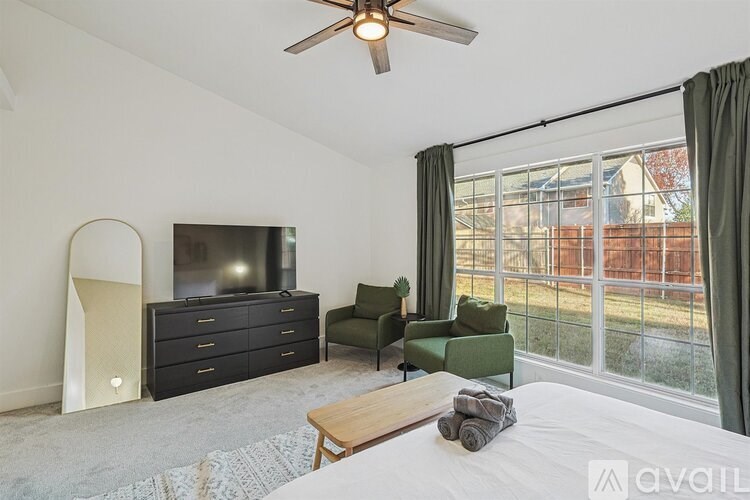 A bedroom with a large bed, a flat screen TV, and a sliding glass door leading to a backyard.