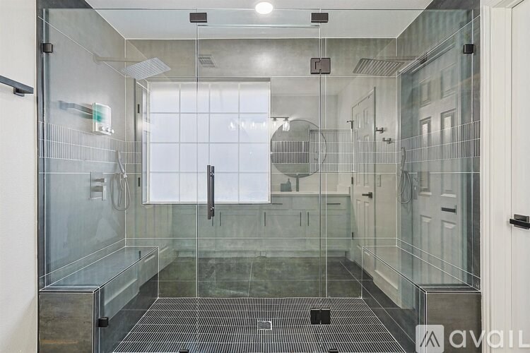 A bathroom with a glass shower stall and a glass door.