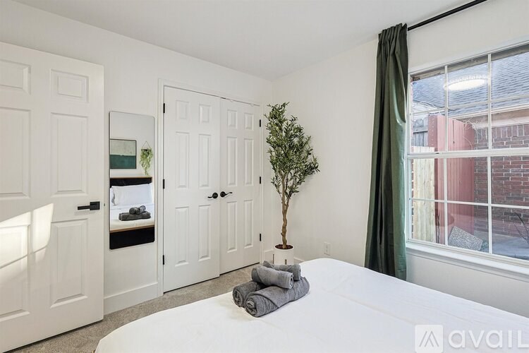 A bedroom with a white bed and a small tree in a white pot.