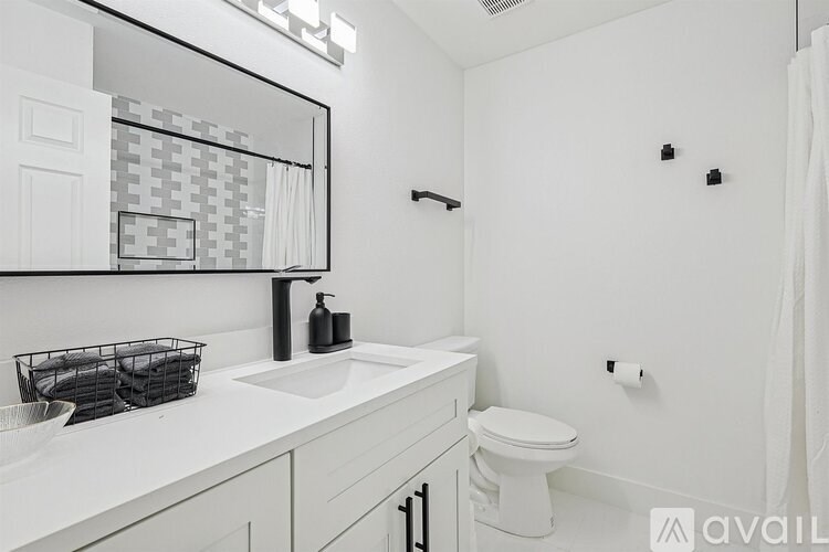 A bathroom with a white toilet, sink, and mirror.