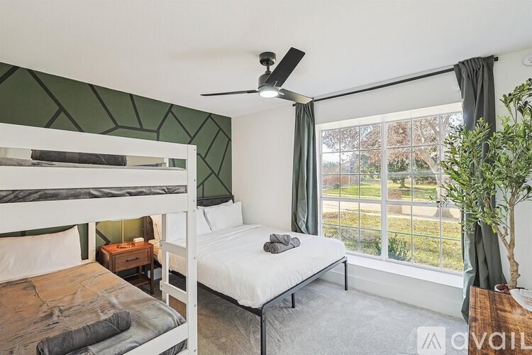 A bedroom with a bunk bed and a single bed with a window view.