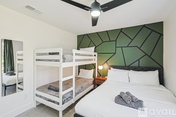 A bedroom with a white bed and a green wallpaper.