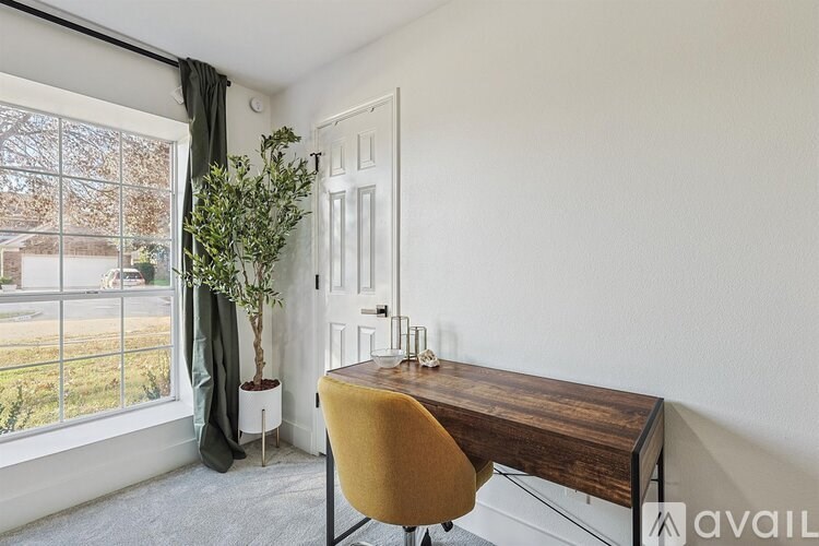 A room with a desk and chair in front of a window.