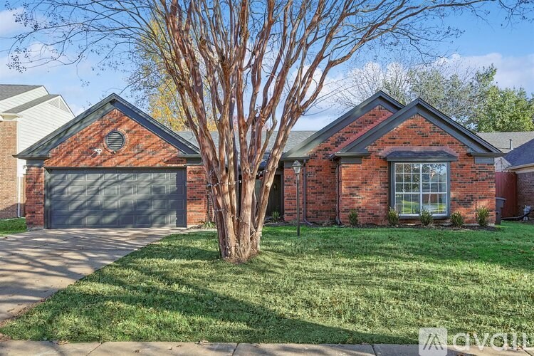 A red brick house with a tree in front.