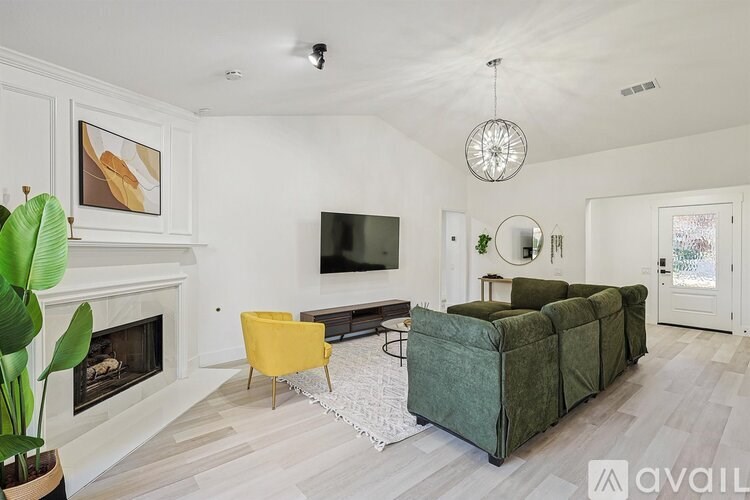 A living room with a green couch, a yellow chair, and a fireplace.