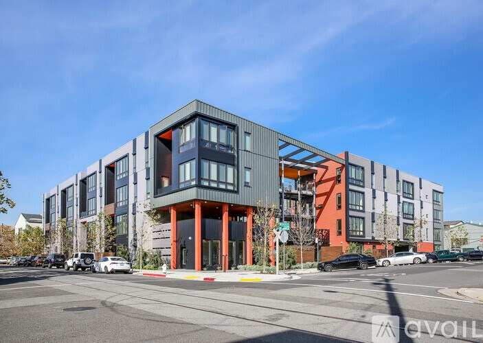 A modern multi-story building with a mix of grey, orange, and blue colors.