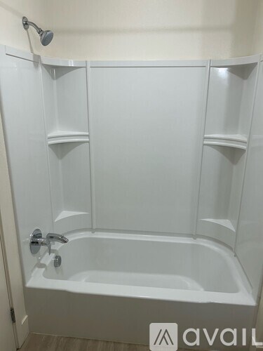 A white bathtub with a shower head and faucet.
