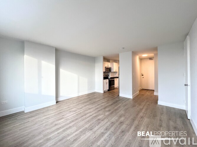 A spacious kitchen with white cabinets and a refrigerator is visible in the image.