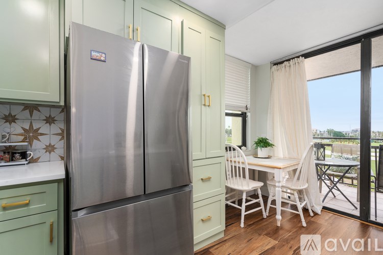 A kitchen with a stainless steel refrigerator and a dining area with a table and chairs.