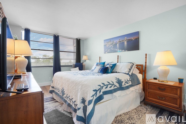 A bedroom with a bed, nightstands, and a window with blinds.