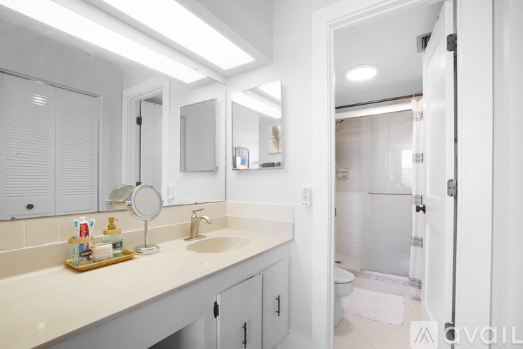 A bathroom with a sink, mirror, and shower.