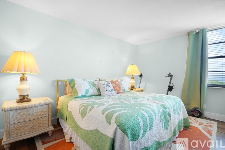 A bedroom with a bed, two lamps, and a nightstand.