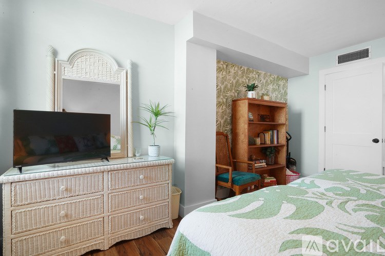 A bedroom with a bed, a dresser, a mirror, and a bookshelf.