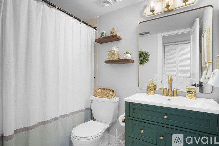 A bathroom with a white toilet, a green vanity, and a shower curtain.