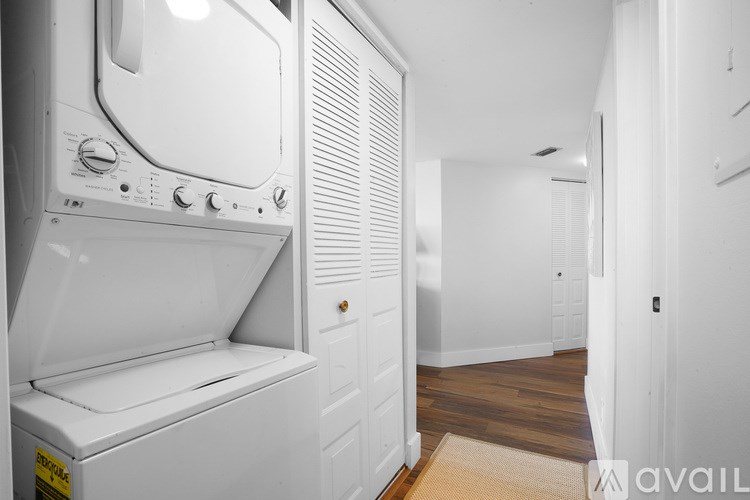 A white washing machine is in a small room with a door on the right.