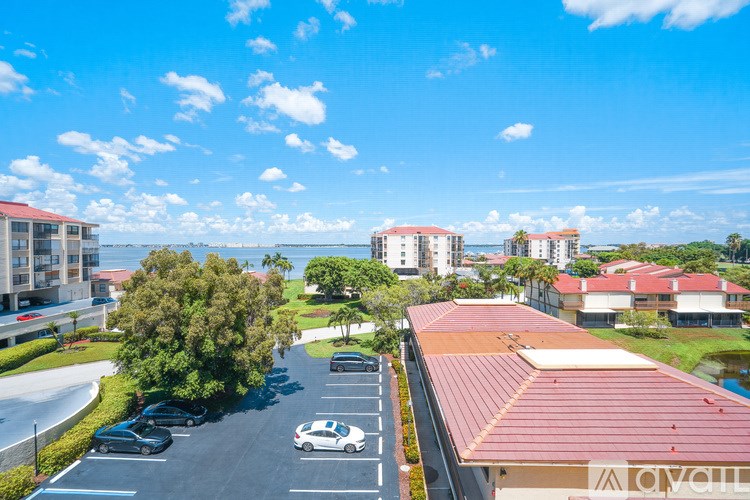 A parking lot with cars and a building with a red roof in the background.
